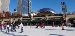 A group of people ice skating on the McCormick Tribune Ice Rink in Millennium Park, Chicago, on a bright, sunny day.