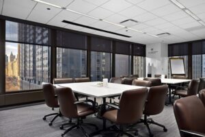 Meeting room at Summit Chicago with leather conference chairs, white tables, a flip chart, and floor-to-ceiling windows overlooking the downtown Chicago skyline.