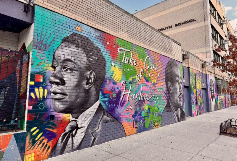 Gemini said A vibrant street mural on a brick wall in Harlem, New York. The mural features large, grayscale portraits of influential Black figures, including the poet Claude McKay