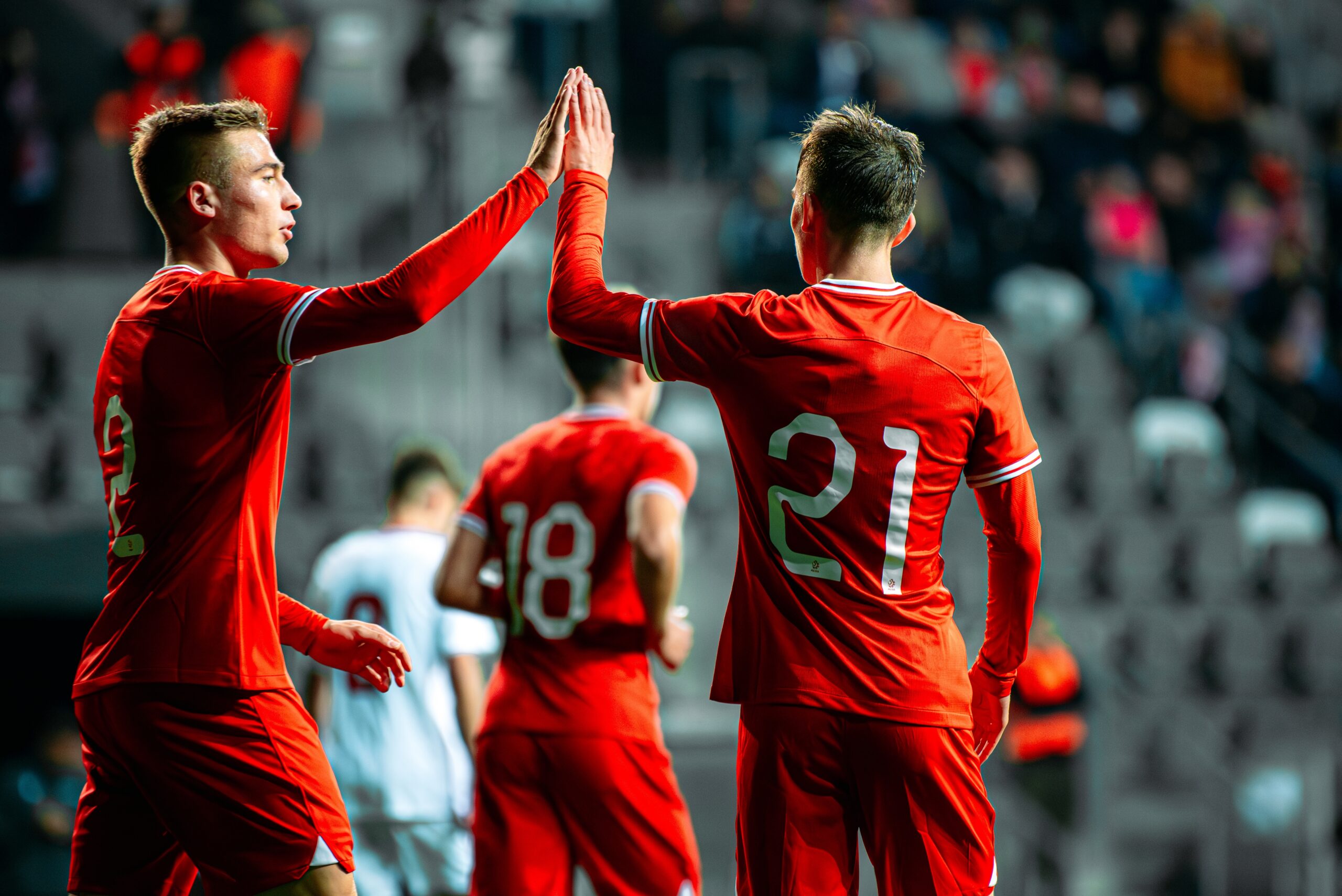 Two soccer players in red jerseys giving a high-five on the field during a world championship game.