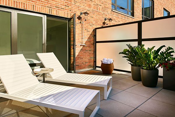 Lounge chairs and potted plants on a terrace at Arlo SoHo Hotel