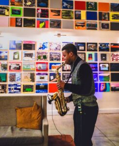 Man playing gold trumpet in bright room with colorful pictures on wall