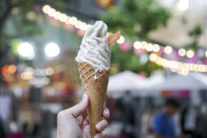 person holding vanilla ice cream cone outdoors with background out of focus
