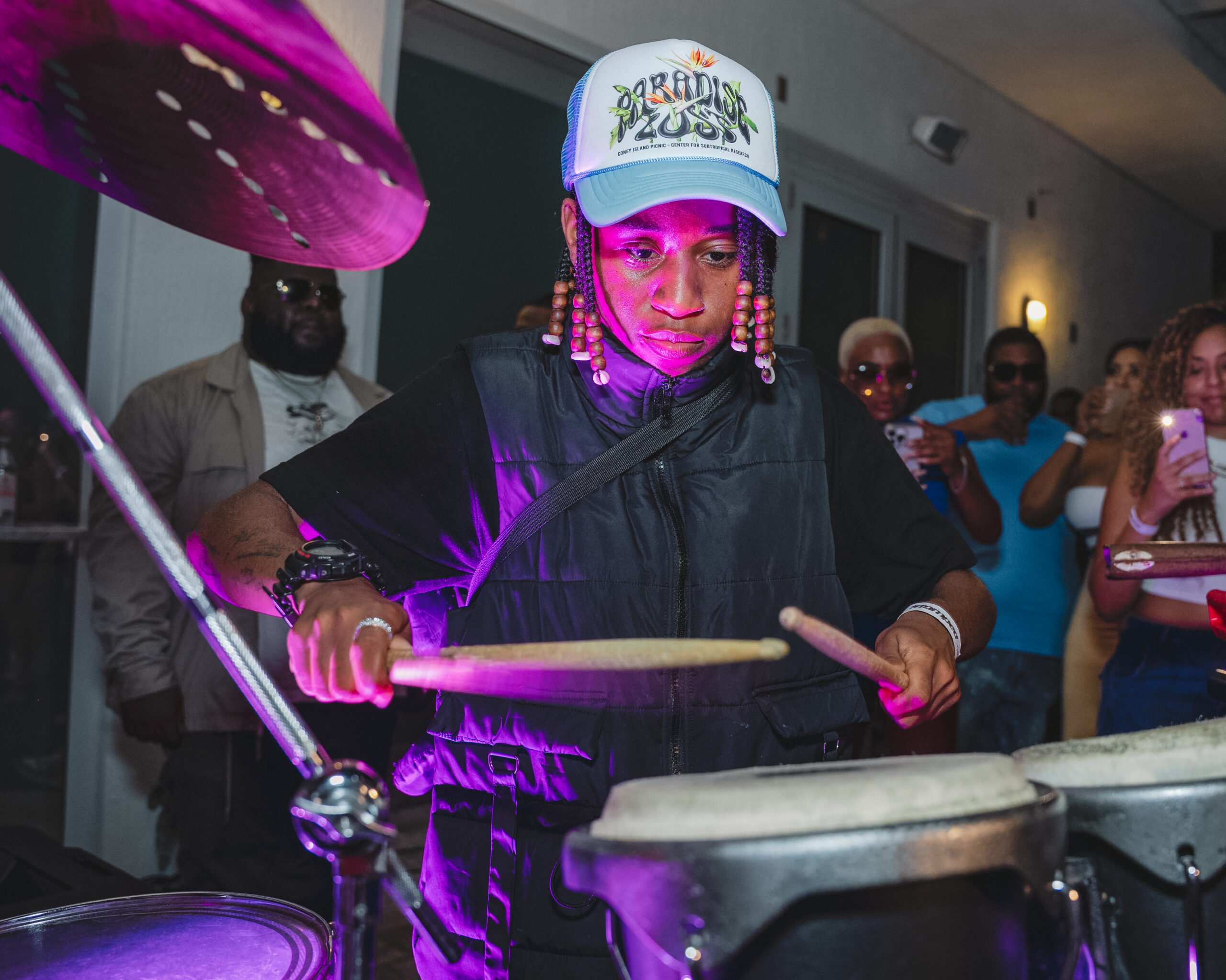 Man playing the drums with a crowd behind him