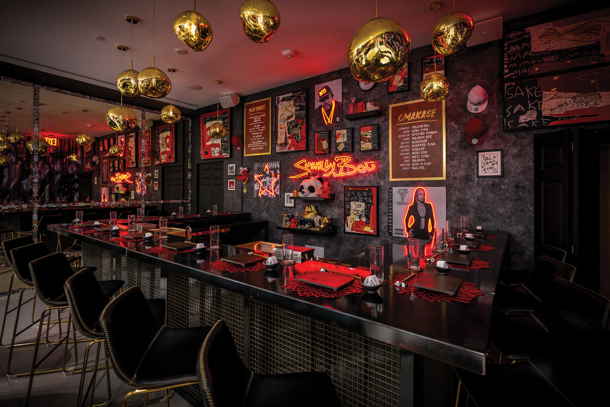 A trendy restaurant interior with modern black seating, neon red lighting, and eclectic wall art, including framed pictures and gold hanging decorations. Tables are set for dining.