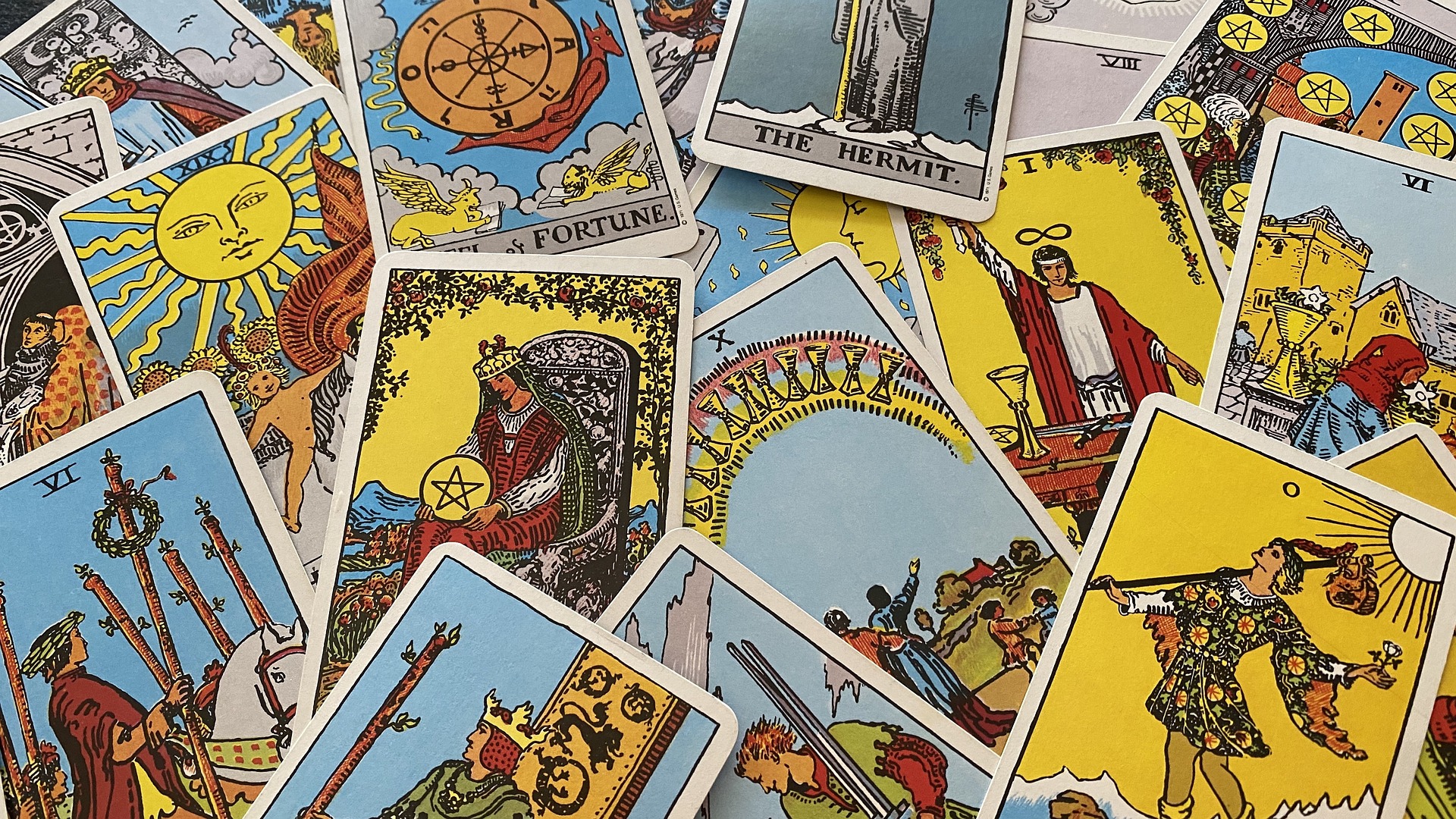 A scattered arrangement of tarot cards displaying various symbols and imagery including The Hermit, The Magician, and The Sun.