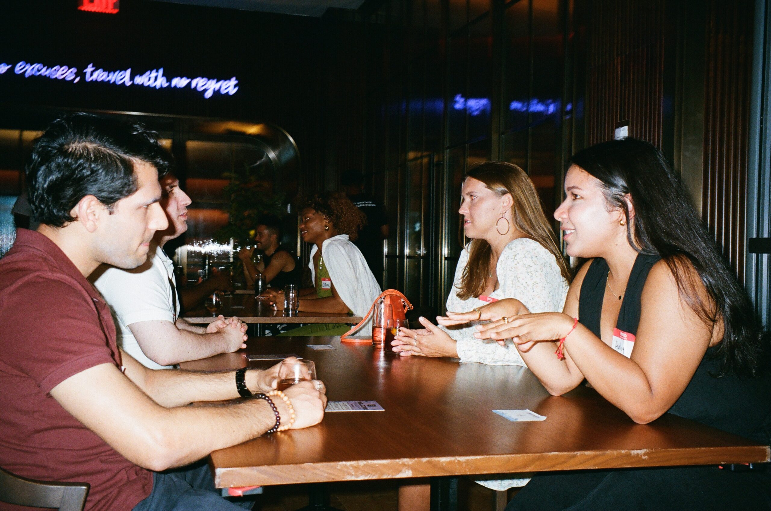 A group of people sitting around a table having a discussion in a dimly lit room.