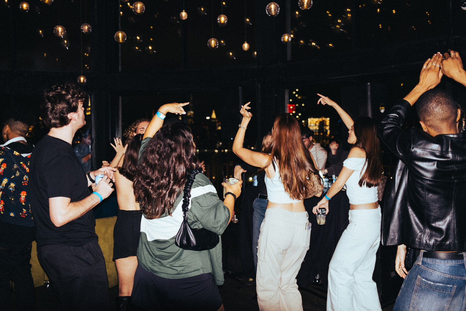 A group of people dancing in a dimly lit room with hanging lights.