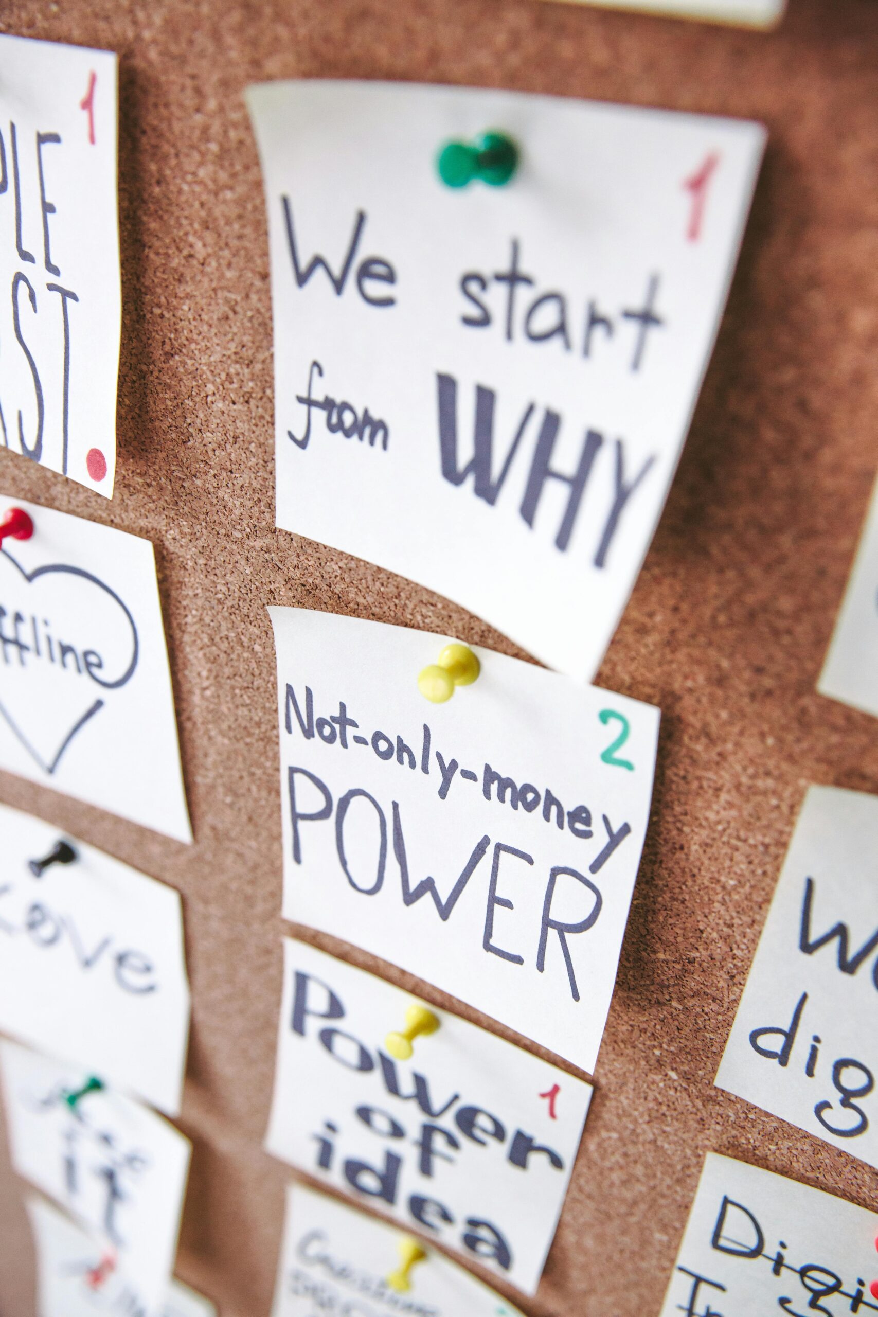 Post-it notes pinned to a corkboard display handwritten phrases such as "We start from WHY" and "Not-only-money POWER," each labeled with a number.