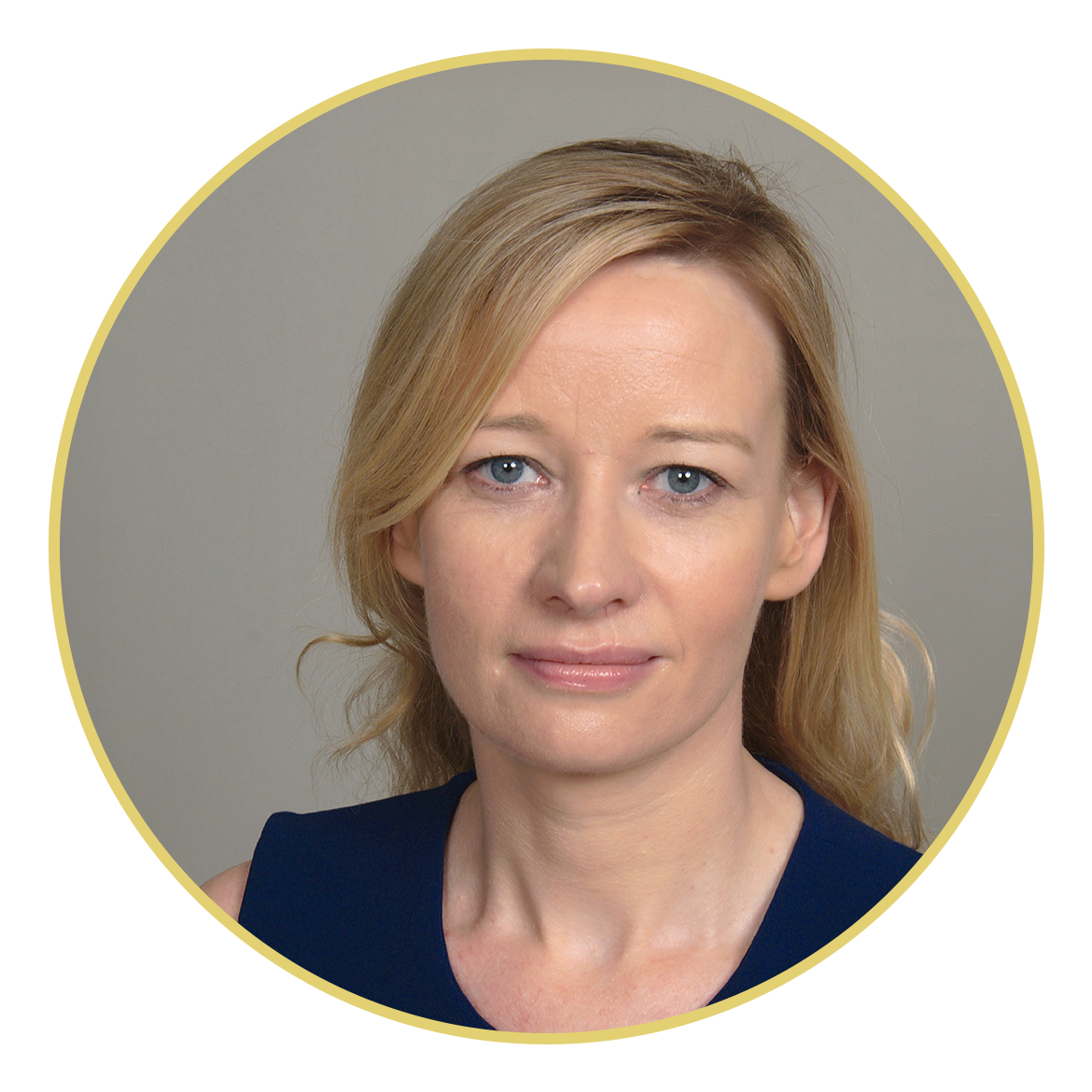 Portrait of a woman with blonde hair wearing a sleeveless navy top, looking directly at the camera against a plain light background.