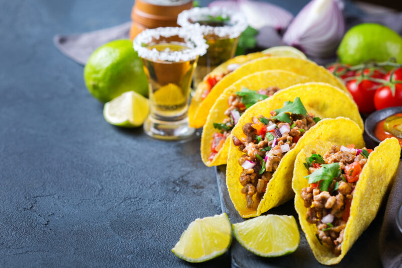 Street-style tacos filled with seasoned meat and fresh toppings served with tequila shots, lime wedges, and colorful ingredients inspired by Wynwood’s vibrant Mexican food scene.