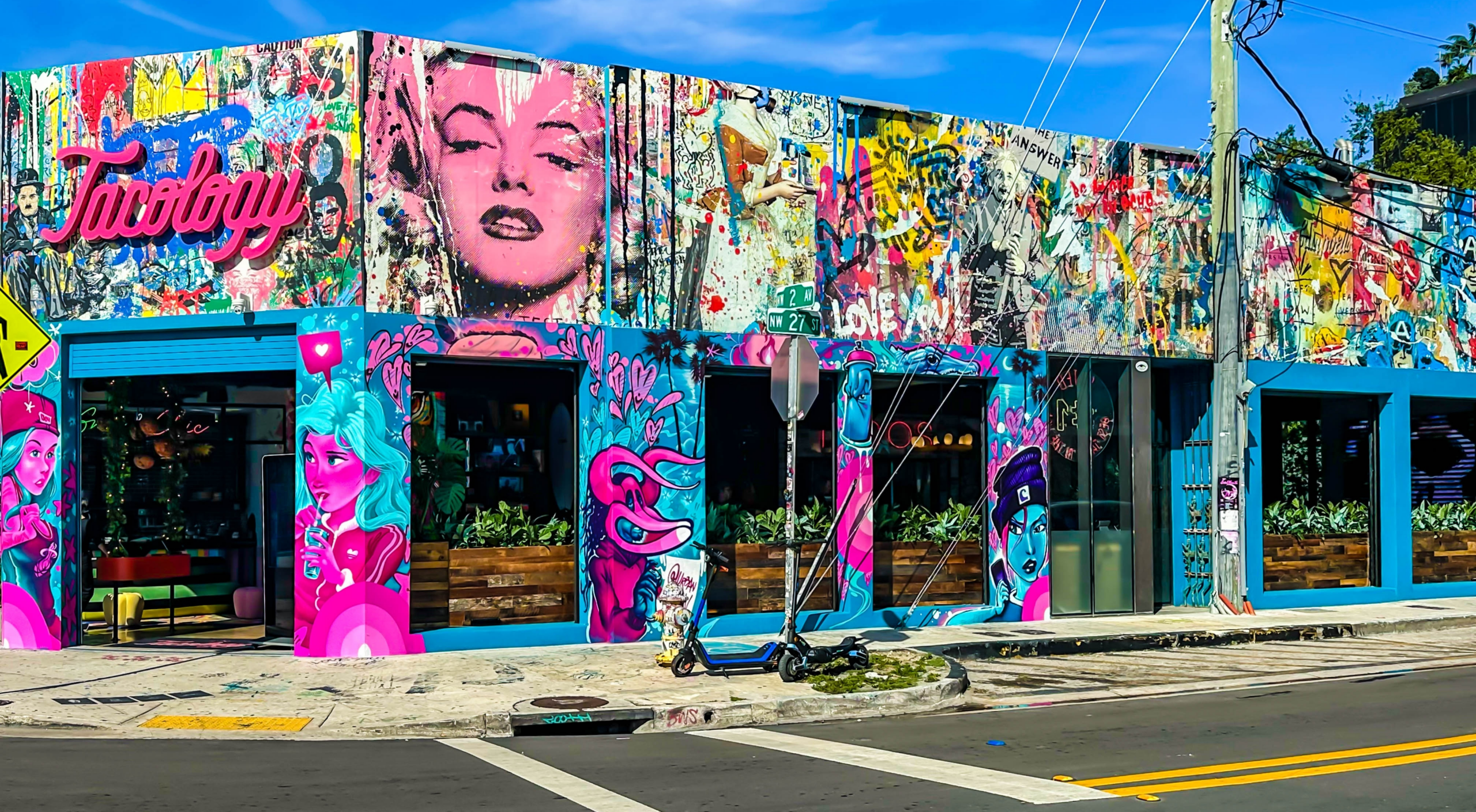 A vibrant Wynwood Walls mural-covered building in Miami, featuring colorful pop-art portraits, graffiti, and street art.